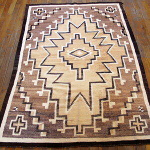 Geometric rug featuring a central star in dark brown, tan, and cream on a plank hardwood floor.