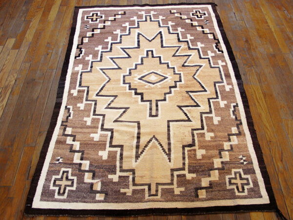 Geometric rug featuring a central star in dark brown, tan, and cream on a plank hardwood floor.