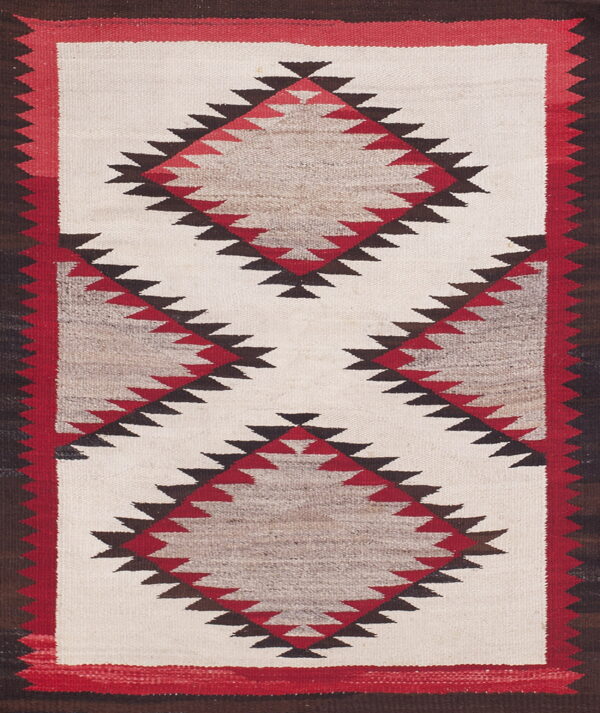 Flatweave rug with serrated red, brown, and natural-toned diamonds on a cream center field.