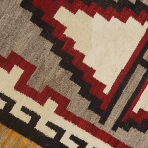 Geometric flatweave rug in red, cream, gray, and black on distressed wood flooring.