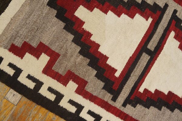 Geometric flatweave rug in red, cream, gray, and black on distressed wood flooring.