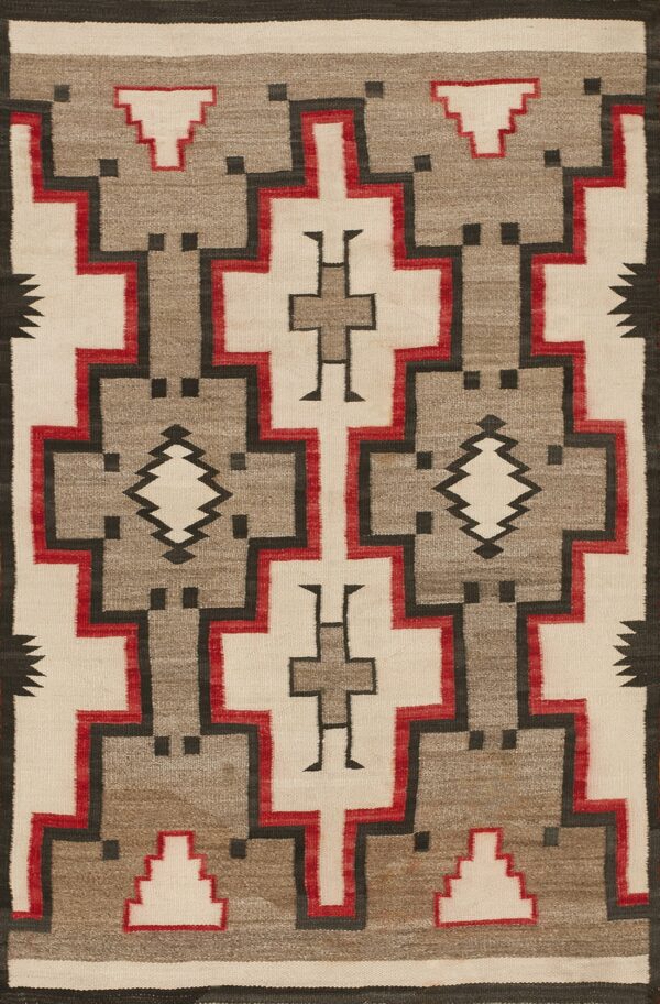 Geometric flat weave rug in cream, gray, red, and black with large interlocking stepped designs.