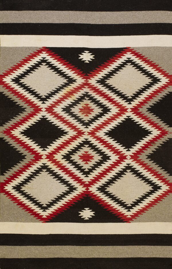 Woven rug with bold stepped diamond designs in black, red, gray, and off-white colors.