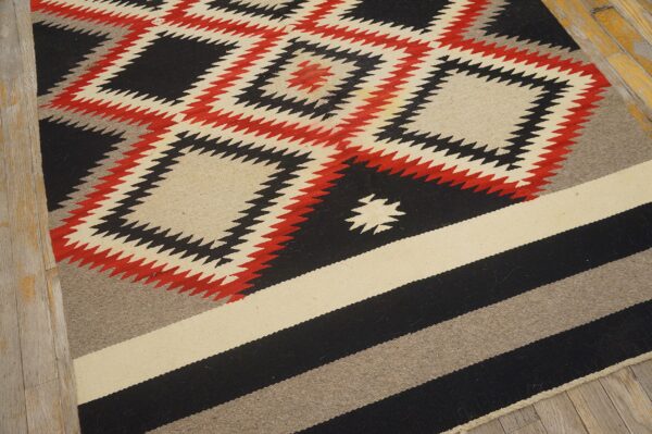 Flatweave rug featuring serrated diamonds in black, red, and cream, transitioning to wide striped bands.