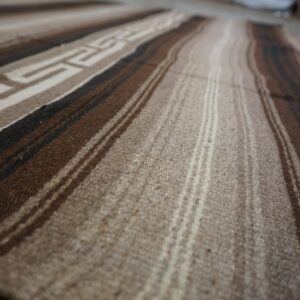 Striped rug in shades of natural brown and tan showing a woven geometric pattern detail.