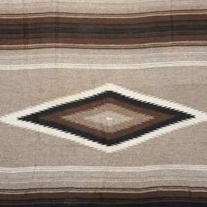 Low-texture rug in tan, brown, and black with horizontal stripes and a central serrated diamond pattern.
