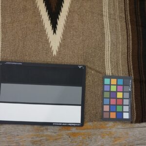 Tan and dark brown flatweave rug with chevron pattern, lying on wood floors beside color charts.