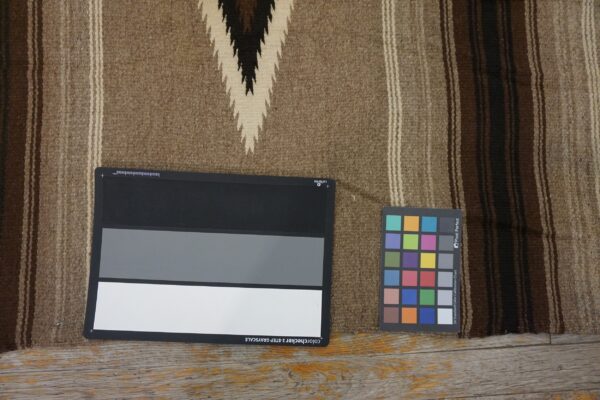 Tan and dark brown flatweave rug with chevron pattern, lying on wood floors beside color charts.