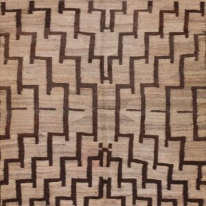 Tan flatweave rug with repeating dark brown stepped geometric shapes creating a continuous pattern.