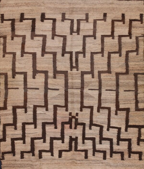 Tan flatweave rug with repeating dark brown stepped geometric shapes creating a continuous pattern.