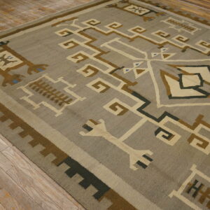 Geometric flatweave rug in gray, cream, brown, and blue rests on rustic light wood flooring.