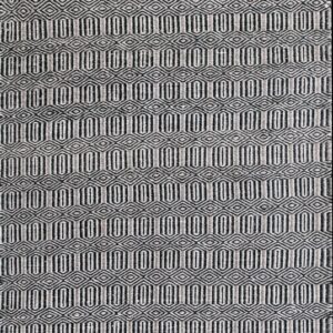 Dark and light geometric runner rug displaying repeating ovals and diamonds on a distressed wood plank floor.