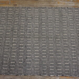 Textured gray and black rug with repeated diamond and elongated hexagon motifs shown on hardwood.