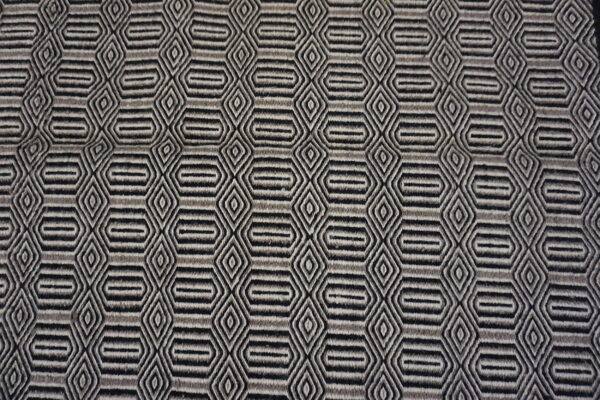 Low-pile rug with alternating black, gray, and light geometric hexagonal and diamond repeating motifs.