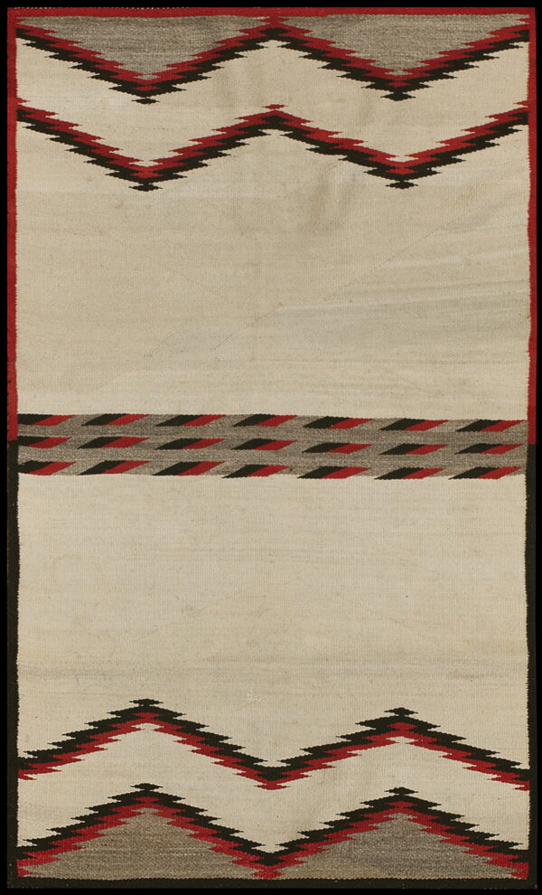 Low pile cream rug featuring bold red, black, and gray serrated zig-zag and diamond patterns.