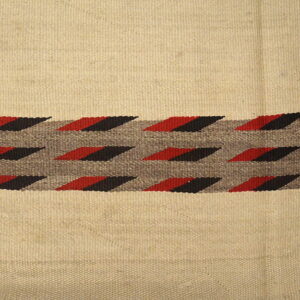 Flatweave rug features a tan field and a central band of red and black geometric designs.