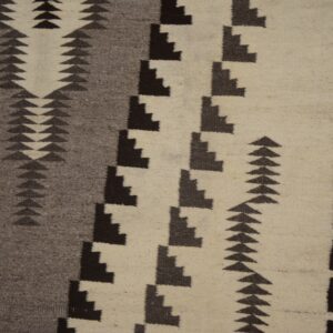 Flatwoven rug detail with black, gray, and cream geometric patterns shown next to a wood edge.