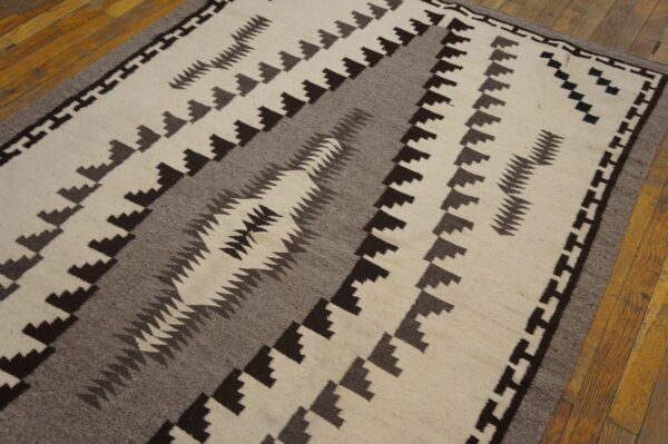 Cream, gray, and brown flat-weave rug with a southwestern style geometric design over hardwood flooring.