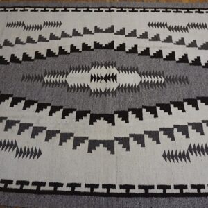 White and gray rug with a bold black geometric pattern and central diamond motif.