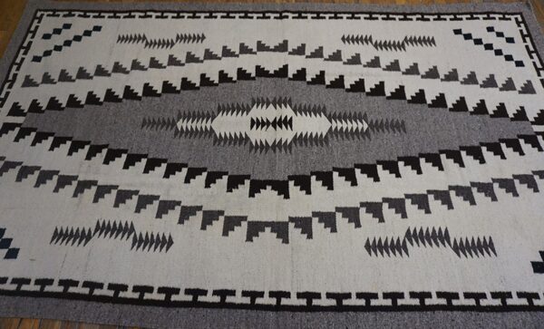 White and gray rug with a bold black geometric pattern and central diamond motif.
