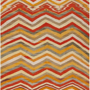 Flat-woven rug featuring wide zig-zag stripes in rust, gold, cream, gray, and brown colors.
