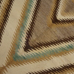 Flatweave rug with serrated zigzag patterns in beige, dark brown, tan, and muted teal.