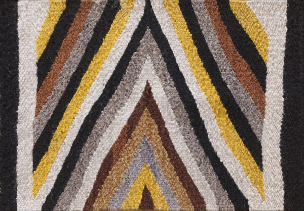 Nubby low-pile rug detail showing geometric chevron stripes in black, cream, yellow, brown, and gray.