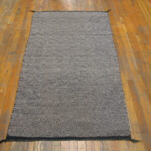 Dark blue and beige woven runner rug with a dense geometric pattern on distressed wood flooring.