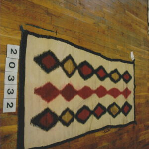 Cream rug with black borders and rows of serrated red and tan diamonds on hardwood floor.