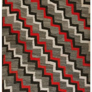 Low-pile rug with a dark gray field and diagonal stepped zigzag pattern in red, black, and off-white.