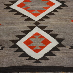 Mottled gray flatweave rug featuring geometric diamonds in orange, white, and dark brown.