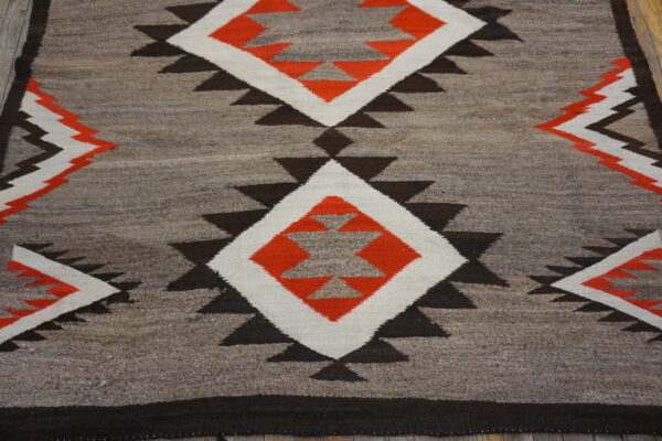 Mottled gray flatweave rug featuring geometric diamonds in orange, white, and dark brown.