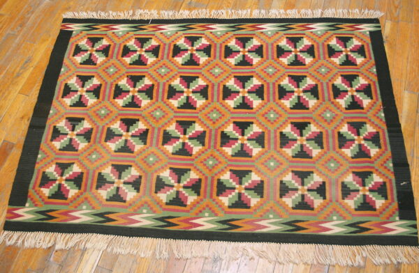 Geometric flatweave rug featuring octagonal medallions and zigzags in orange, deep red, green, and black.