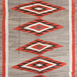 Geometric flatweave rug with stacked red and dark diamond patterns centered on a gray background.
