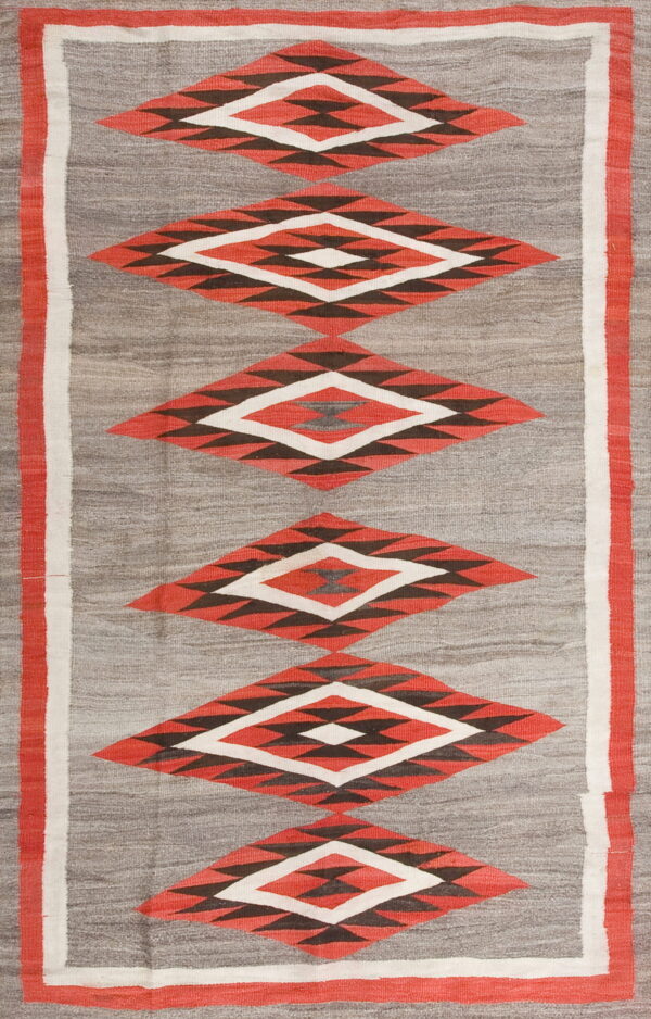 Geometric flatweave rug with stacked red and dark diamond patterns centered on a gray background.