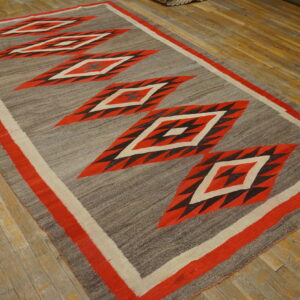 Gray and red flat-weave rug featuring central geometric diamond patterns on rustic wood planks.
