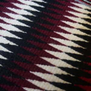 Diagonal black, cream, and burgundy stripes form a sharp, geometric pattern on the low-pile square rug.