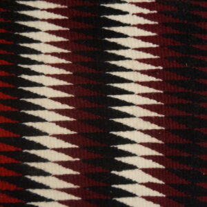 Low-pile square rug featuring interlocking geometric diamonds in cream, black, and deep maroon on wood flooring.