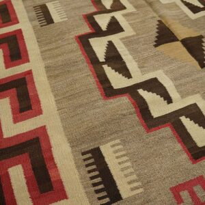 Geometric flatweave rug featuring red, brown, and natural taupe zigzags and a Greek key border.