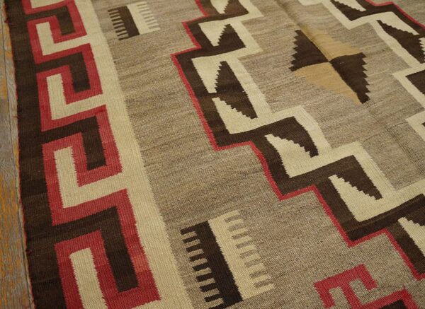 Geometric flatweave rug featuring red, brown, and natural taupe zigzags and a greek key border.