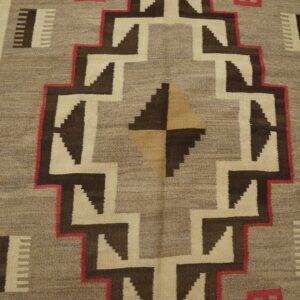 Flatwoven rug featuring bold, stepped geometric designs in tan, dark brown, cream, and bright red.