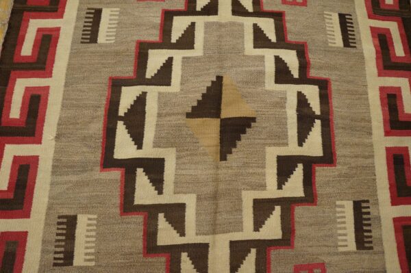 Flatwoven rug featuring bold, stepped geometric designs in tan, dark brown, cream, and bright red.