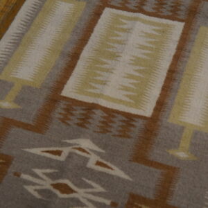 Geometric runner rug with gray, brown, yellow, and cream patterns on wooden floorboards.