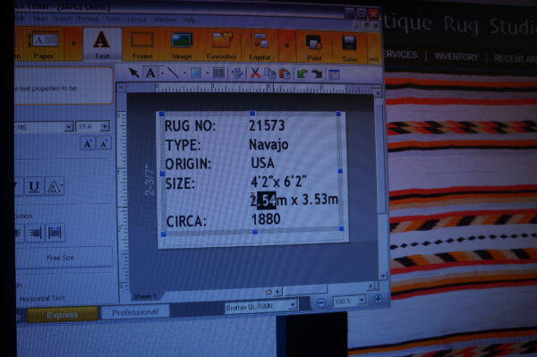 A computer screen displays text fields over a background image of a red, black, and orange striped rug.