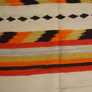 Striped flatweave rug displaying black diamonds, zigzags, and bands of red, orange, gold, and cream on wood.