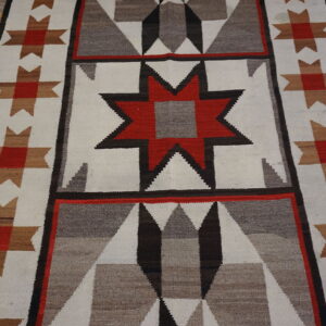 Red, gray, and cream geometric runner rug with a stepped star pattern lies on distressed wood planks.