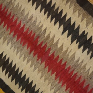 Diagonal zig-zag patterned flatweave rug in cream, black, gray, and red, on hardwood flooring.