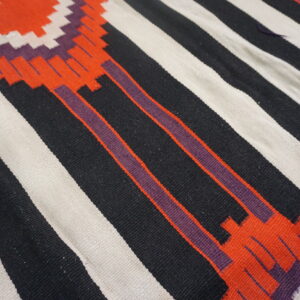 Geometric flatweave rug with bold black, off-white, orange, and purple stripes and stepped motifs.