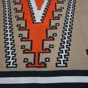 Flat weave rug featuring bold orange, black, white, and tan Southwestern geometric patterns.