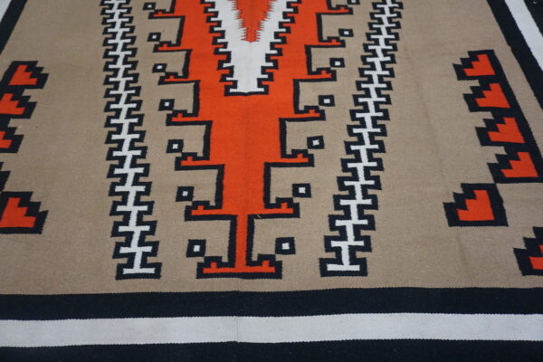 Flat weave rug featuring bold orange, black, white, and tan southwestern geometric patterns.